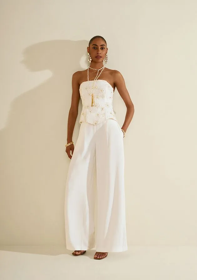 Modelo usando top corselet off-white bordado com calça pantalona branca